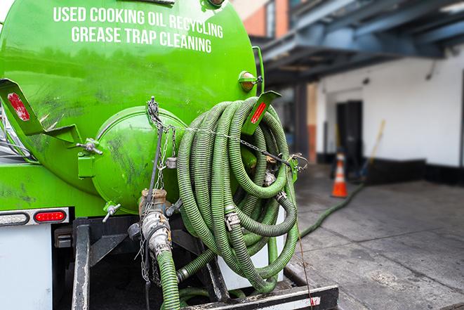 a professional plumber using a pump to empty a grease trap in Annapolis MD